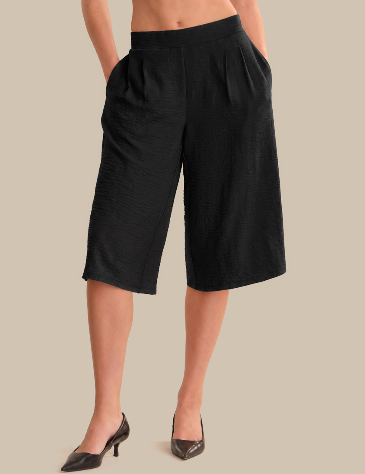 Black wide-leg pants worn by a person on a beige background