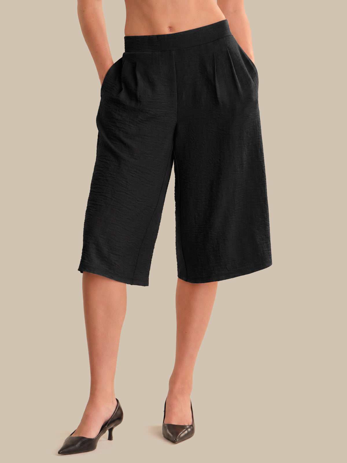 Black wide-leg pants worn by a person on a beige background