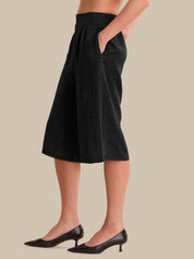 Person wearing black wide-leg pants on a beige background