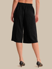 Person wearing black wide-leg pants on a beige background