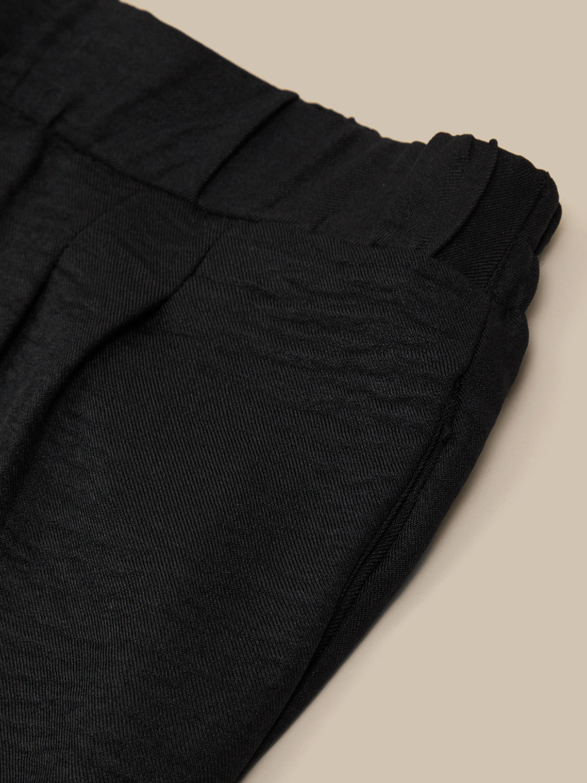 Black pants folded on a beige surface