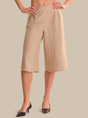 Beige linen shorts worn by a person on a beige background