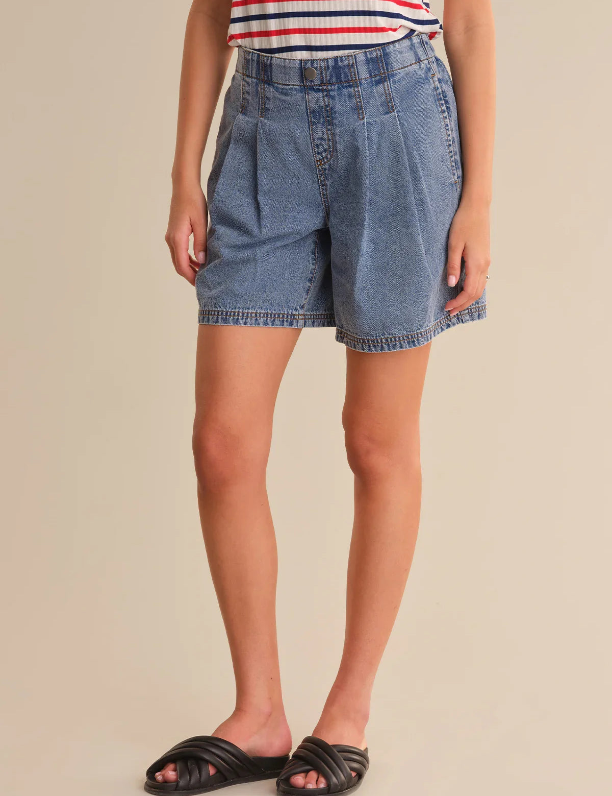 Person wearing blue denim shorts on a beige background