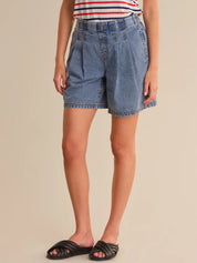 Person wearing blue denim shorts on a beige background