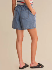 Person wearing a denim skirt with a plain background