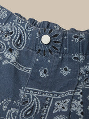 Close-up of blue bandana patterned fabric with a button on a beige background