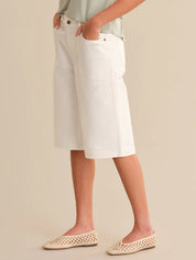 Person wearing white shorts and beige flats on a beige background