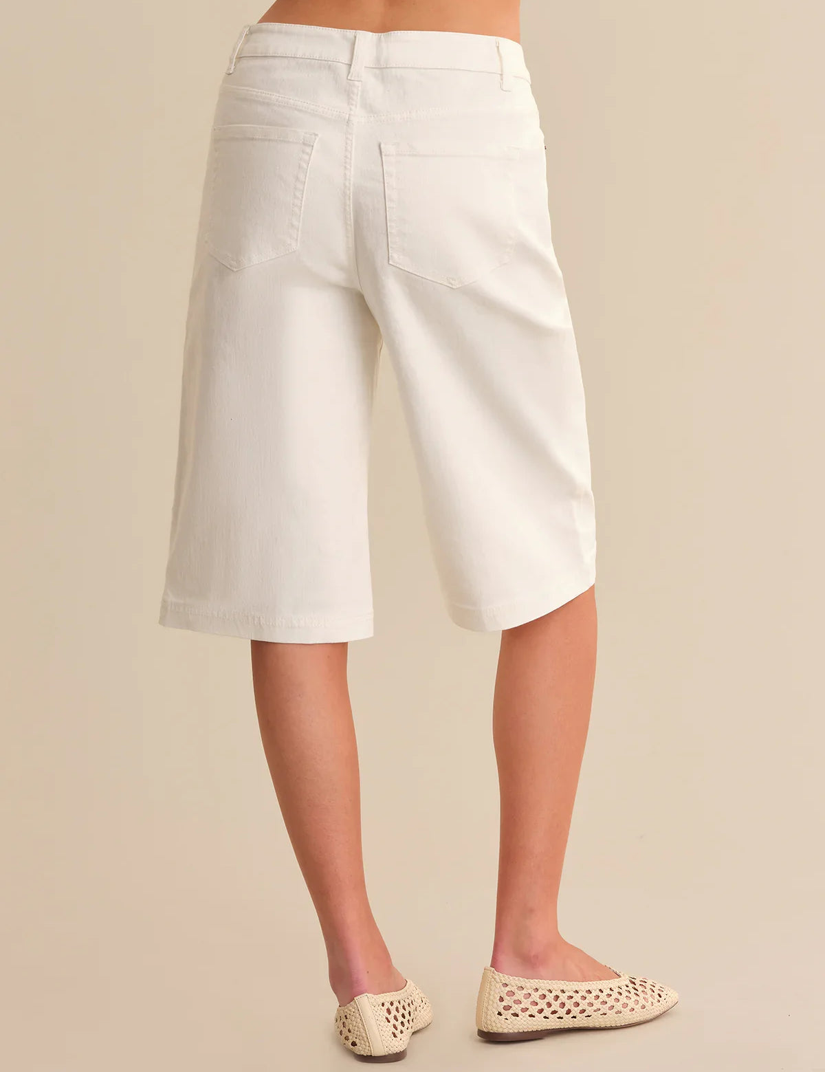 White shorts worn by a person on a beige background