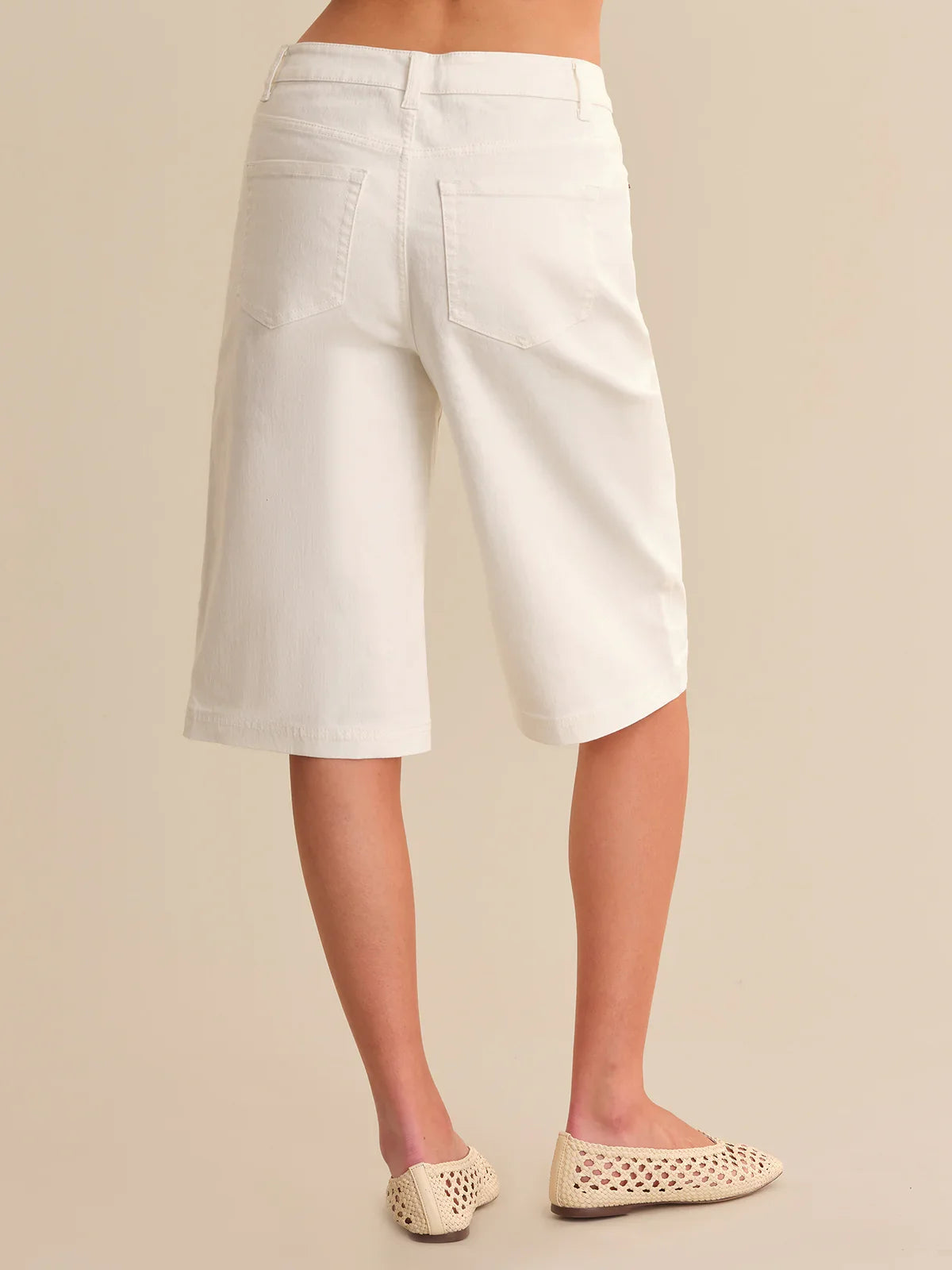 White shorts worn by a person on a beige background