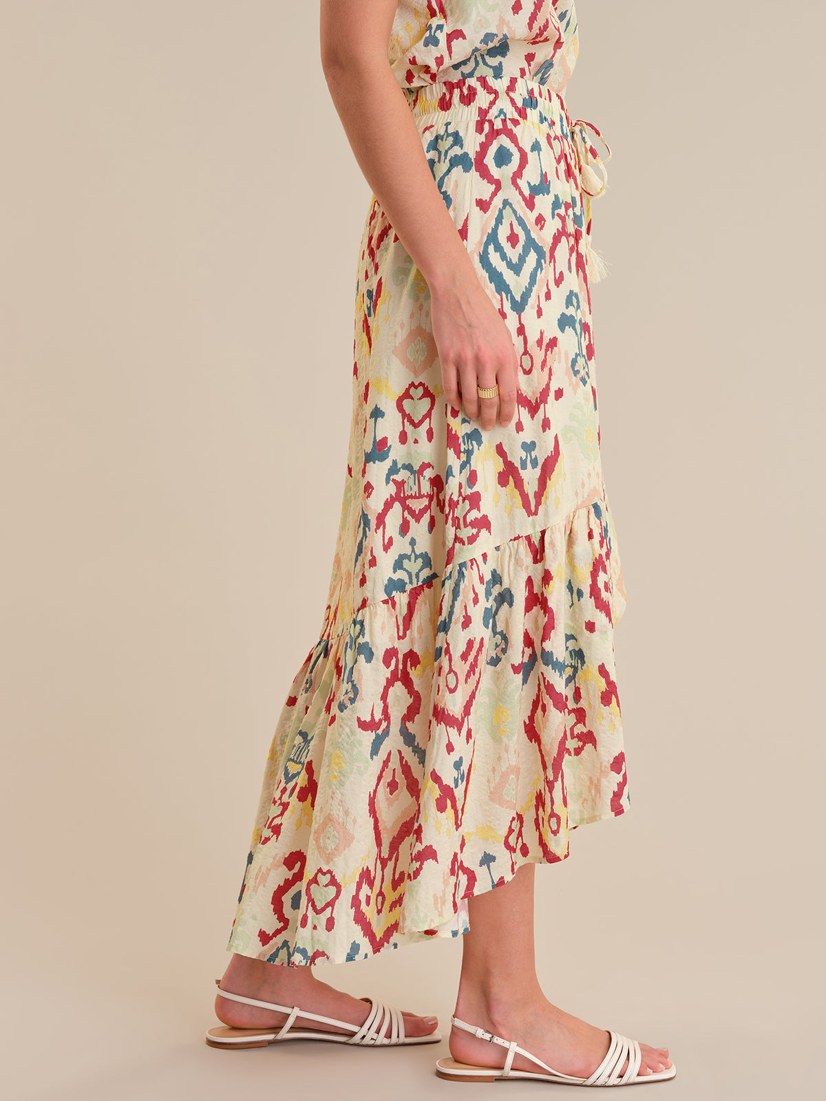 Person wearing a colorful patterned dress on a beige background