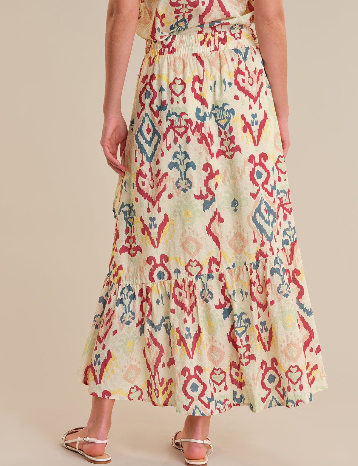 Woman wearing a colorful patterned dress on a beige background