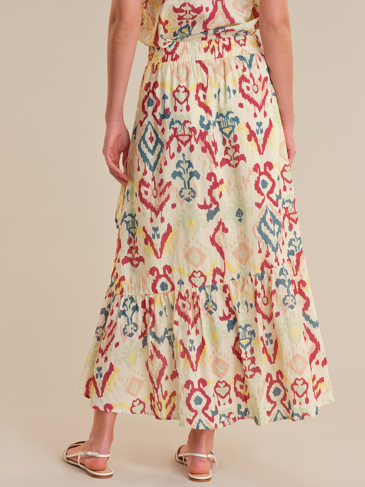 Woman wearing a colorful patterned dress on a beige background