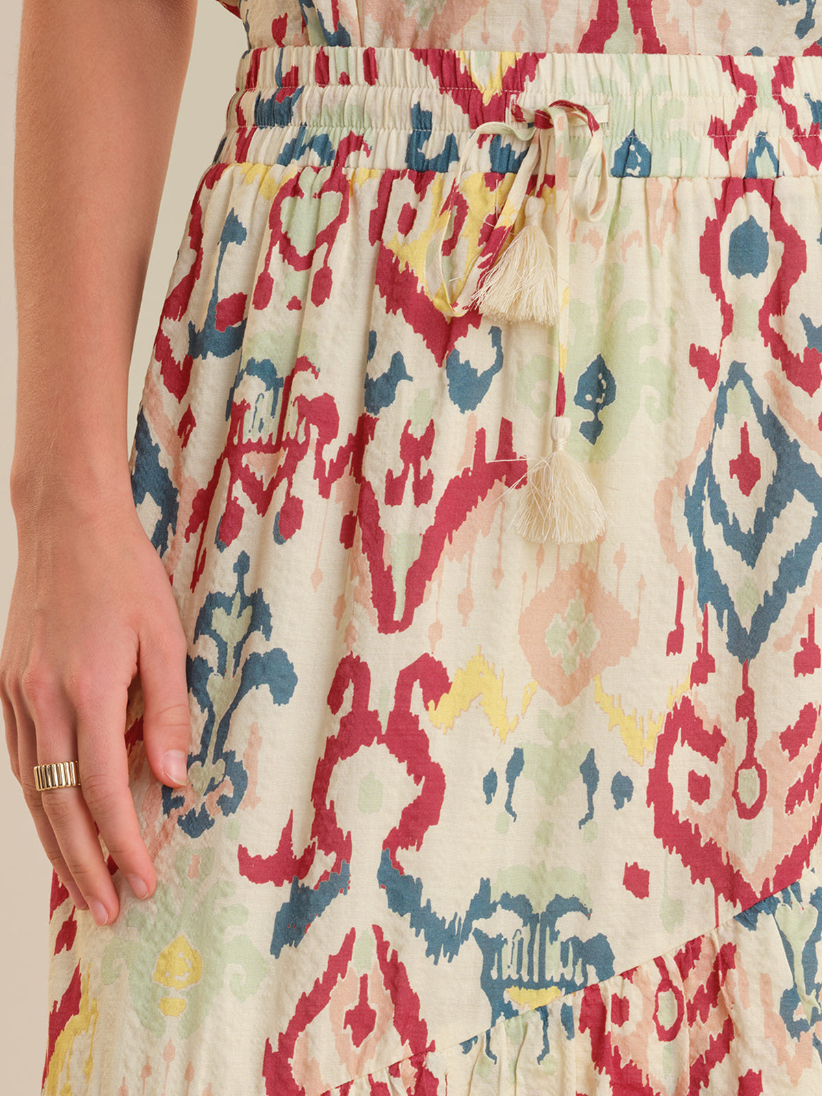 Colorful patterned skirt with tassel detail on a beige background