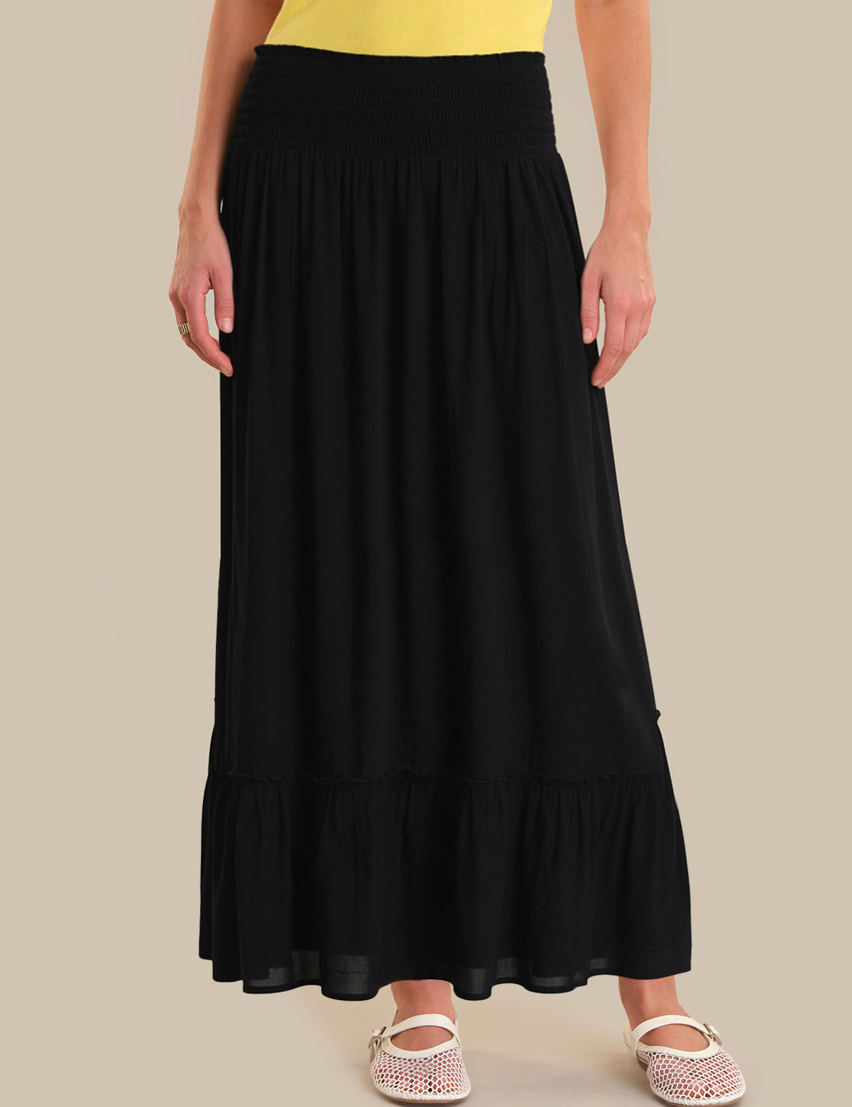 Person wearing a black skirt on a beige background