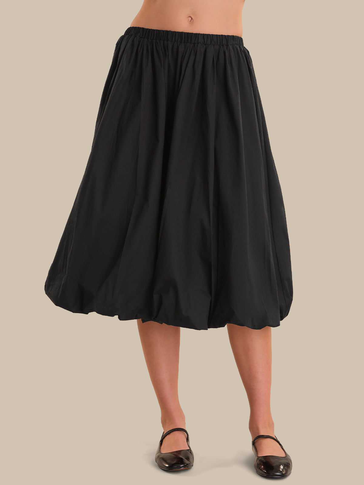 Black skirt worn by a person on a beige background