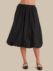 Black skirt worn by a person on a beige background