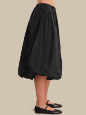 Black skirt worn by a person on a beige background