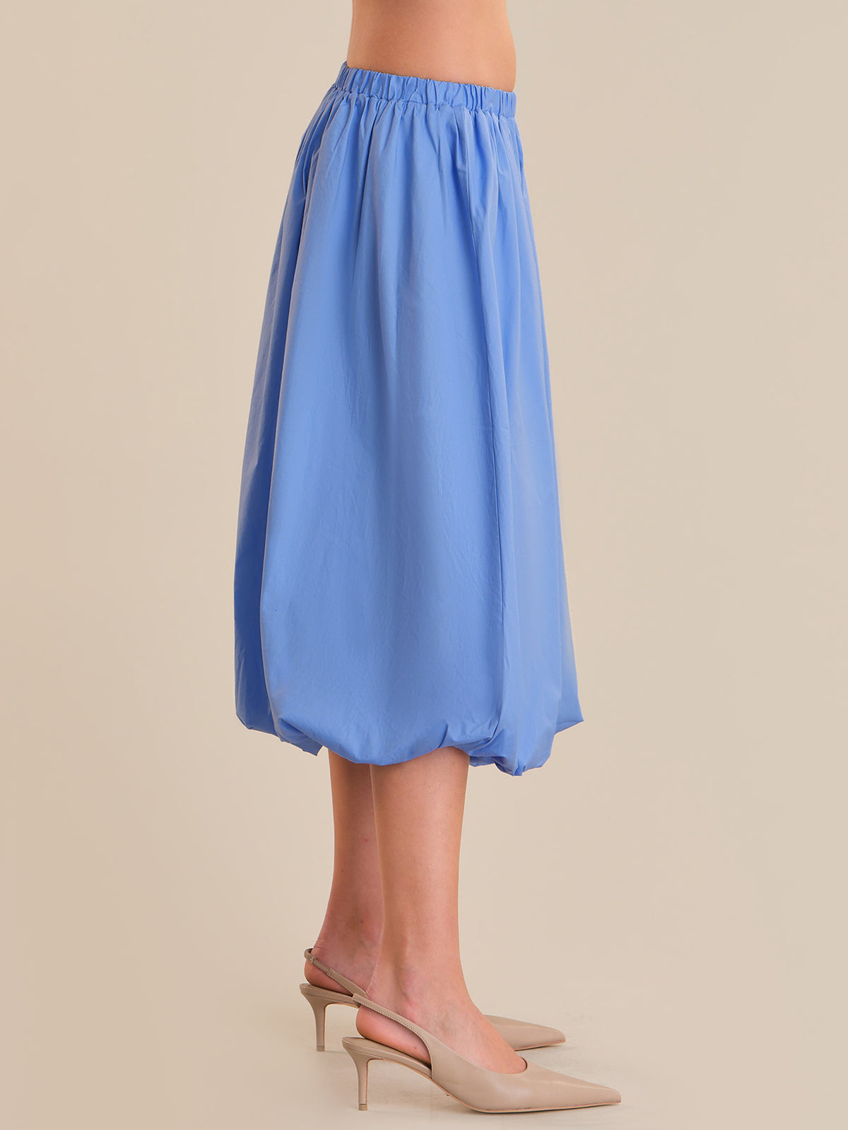 Blue skirt worn by a person on a beige background