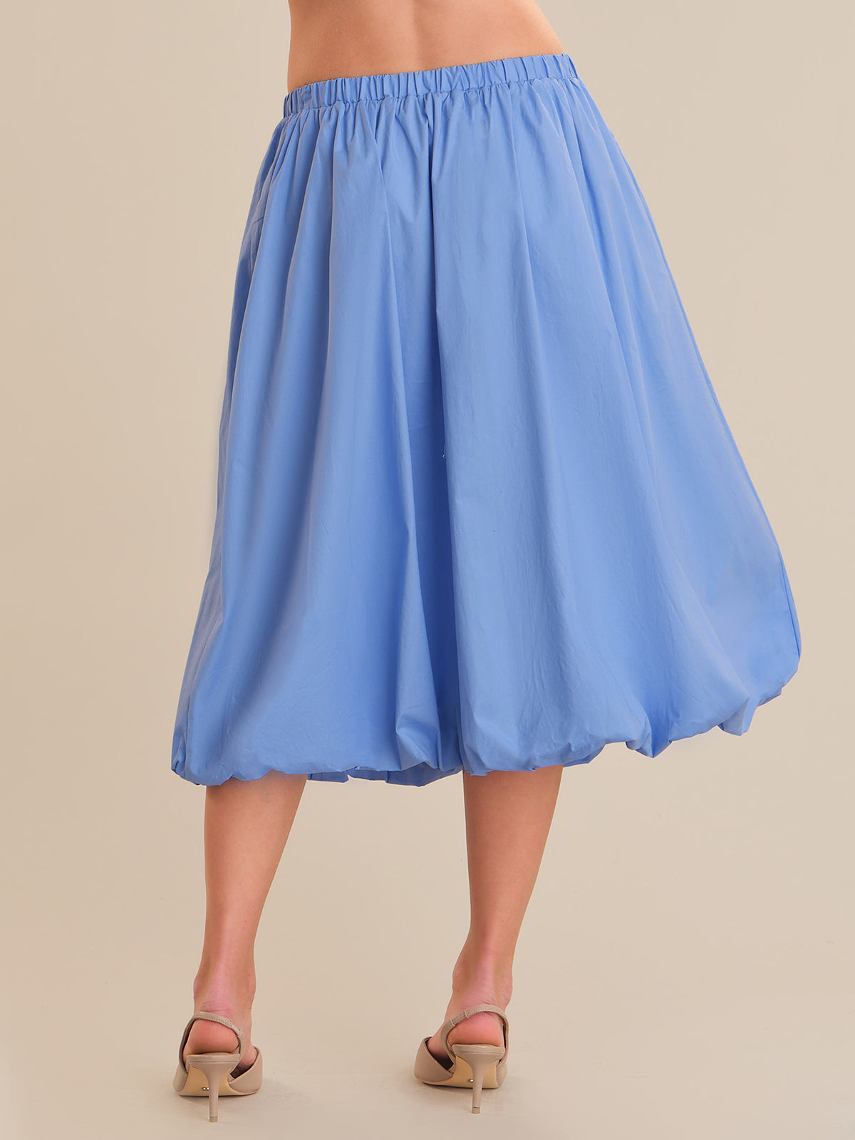 Blue skirt worn by a person on a beige background