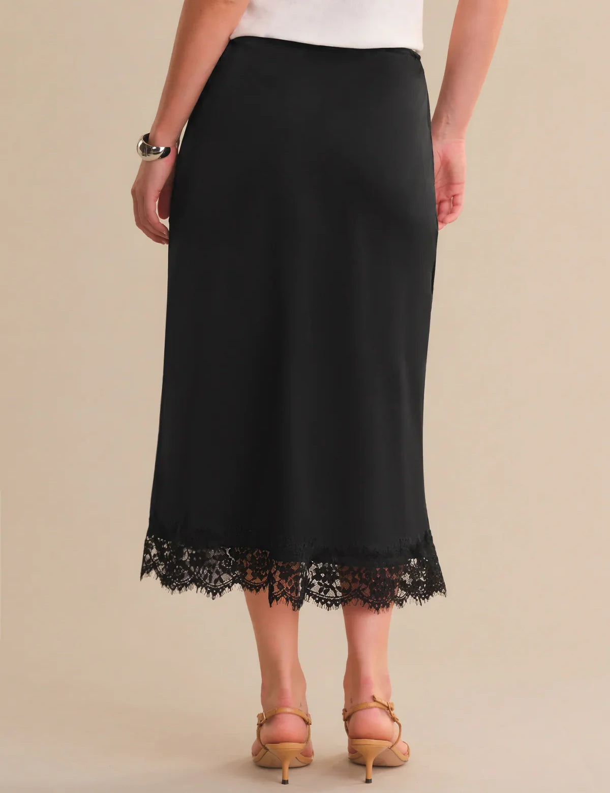Black skirt with lace hem worn by a person on a beige background