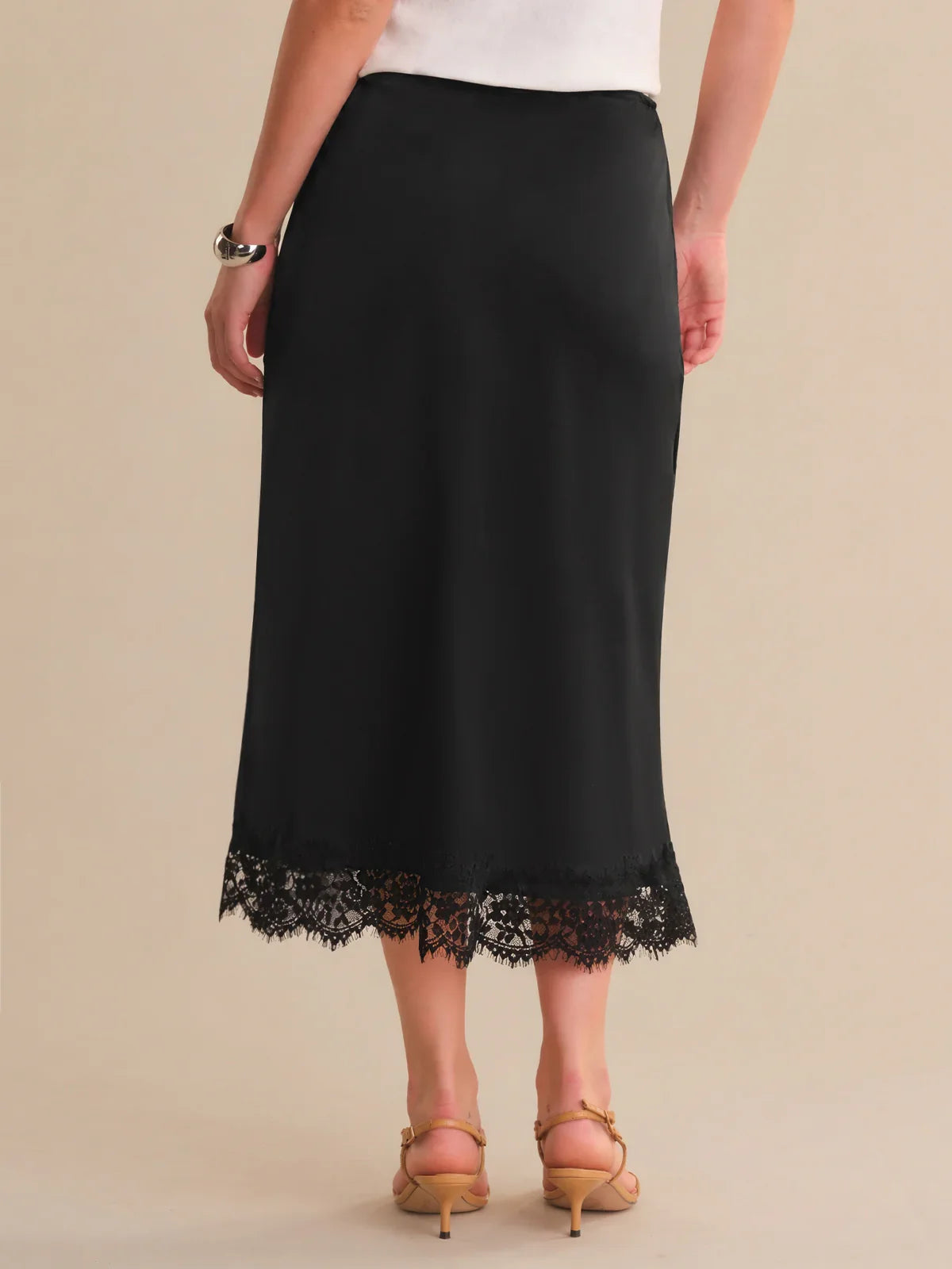 Black skirt with lace hem worn by a person on a beige background