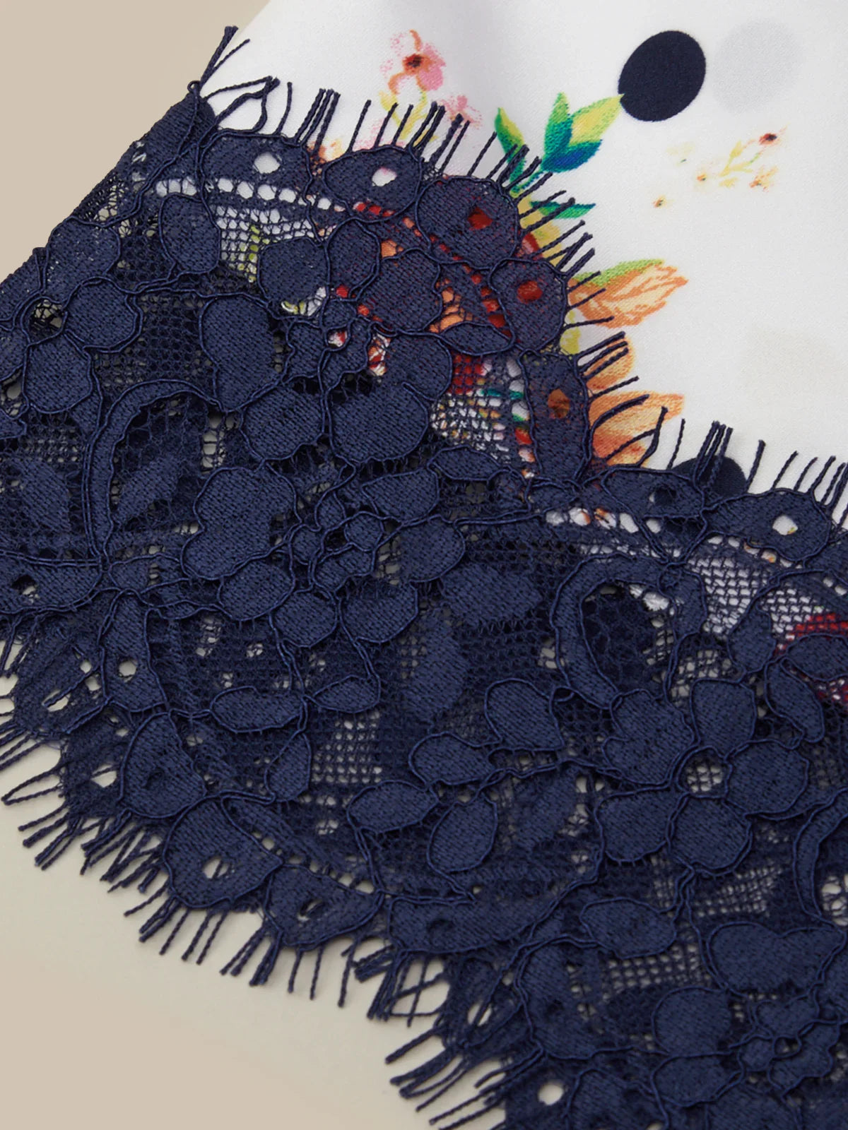 Navy blue lace fabric with colorful floral design in the background