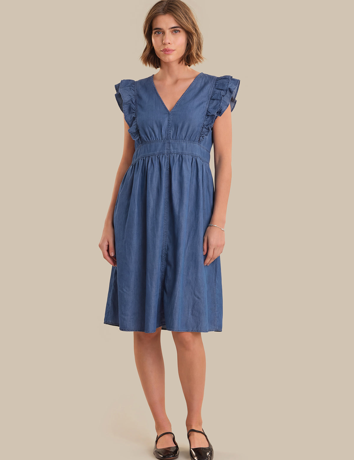 Woman wearing a blue dress against a beige background