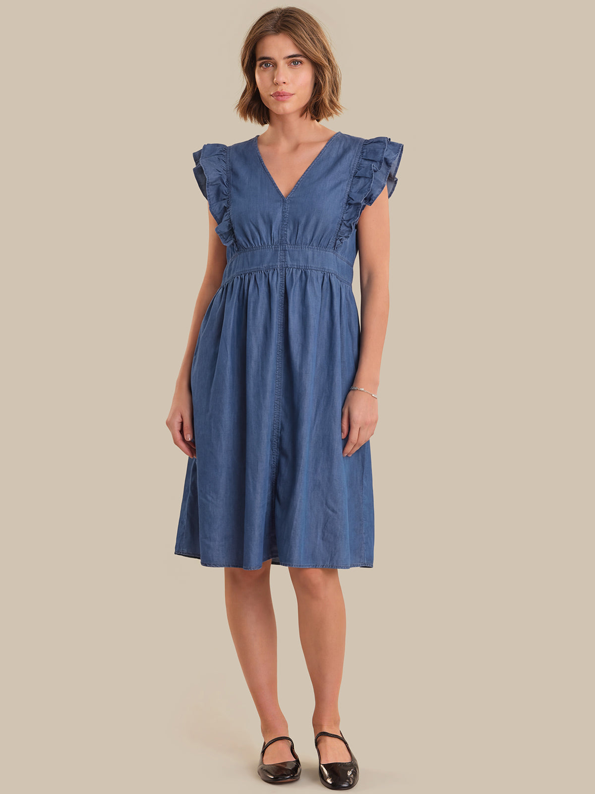 Woman wearing a blue dress against a beige background