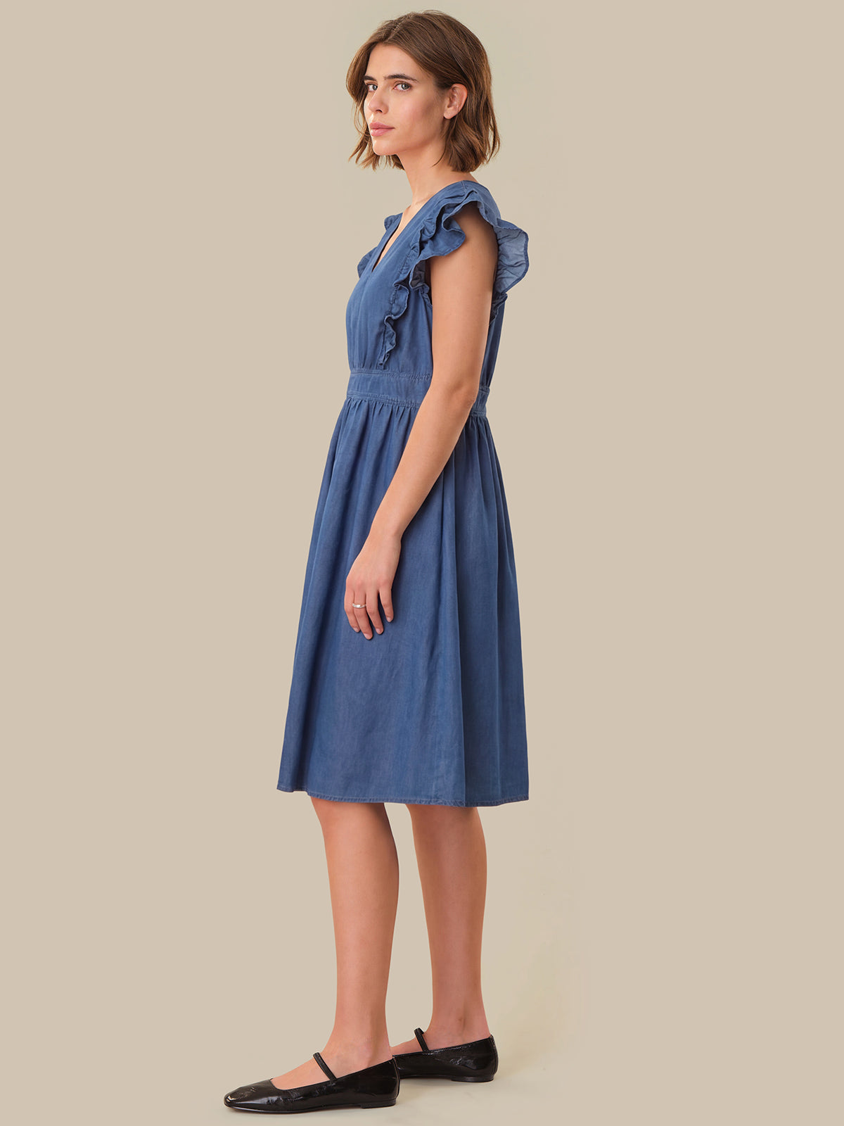 Woman wearing a blue dress against a beige background