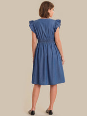 Woman wearing a blue dress with ruffled sleeves on a beige background