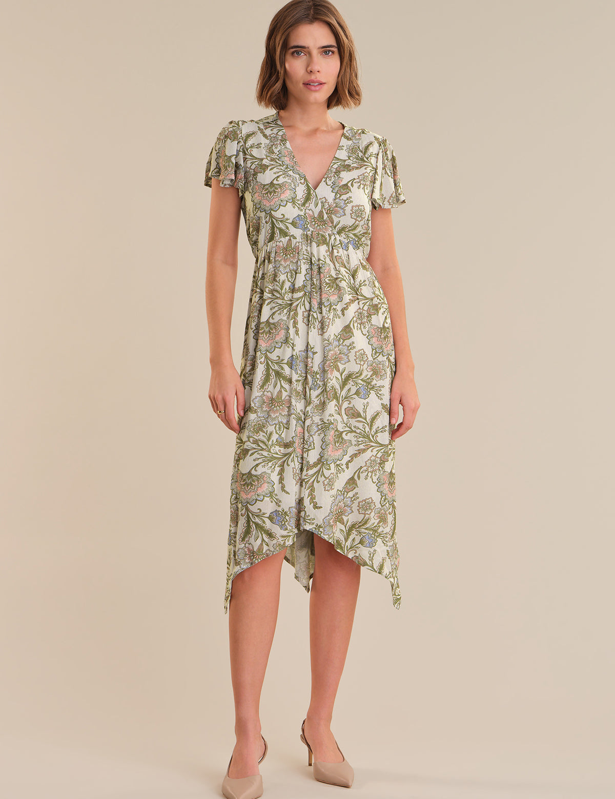Woman wearing a green floral dress on a beige background