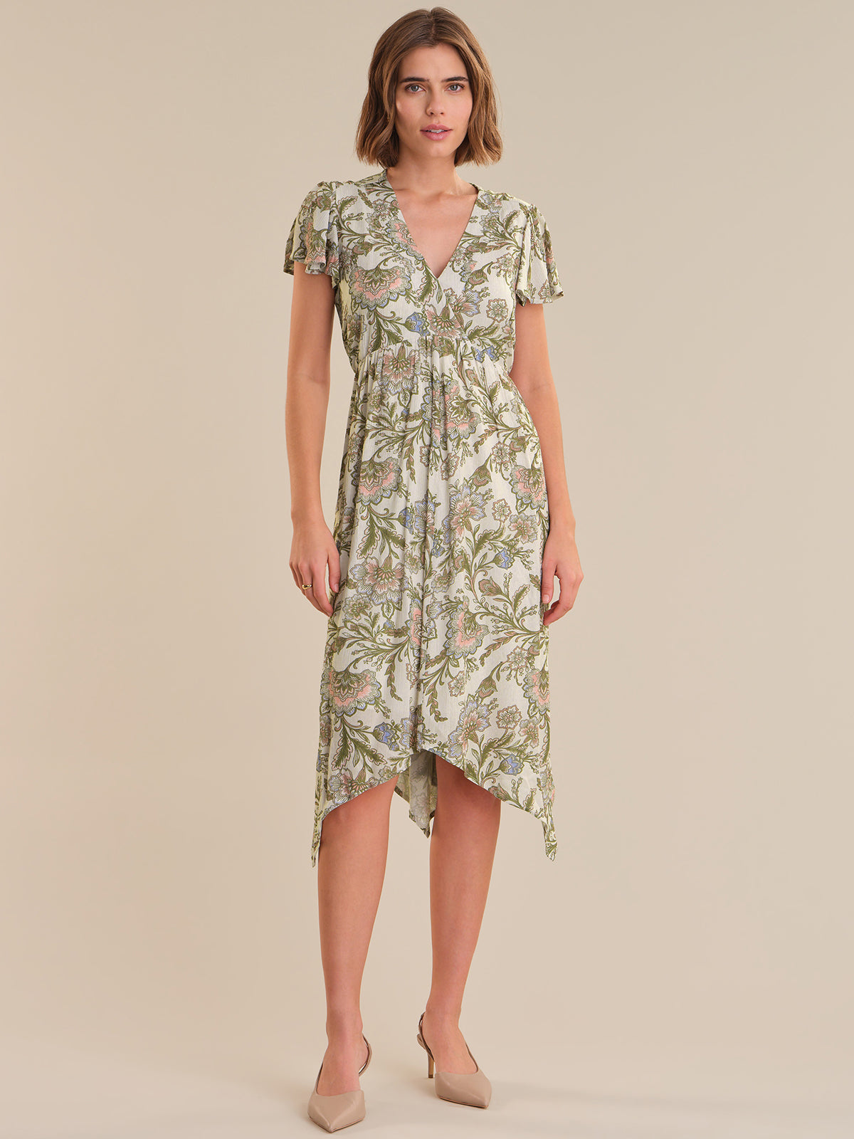 Woman wearing a green floral dress on a beige background