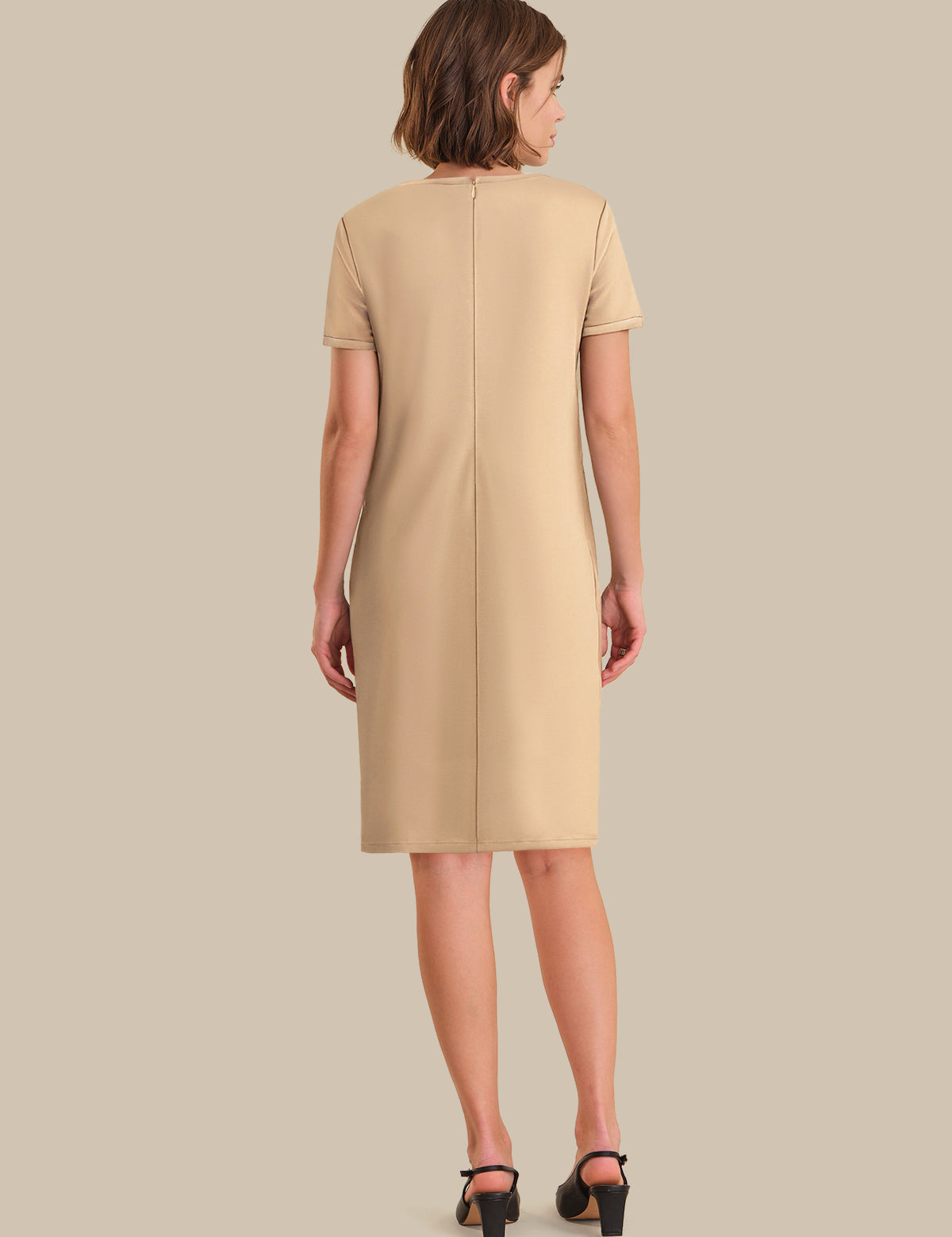 Woman wearing a beige dress against a plain background