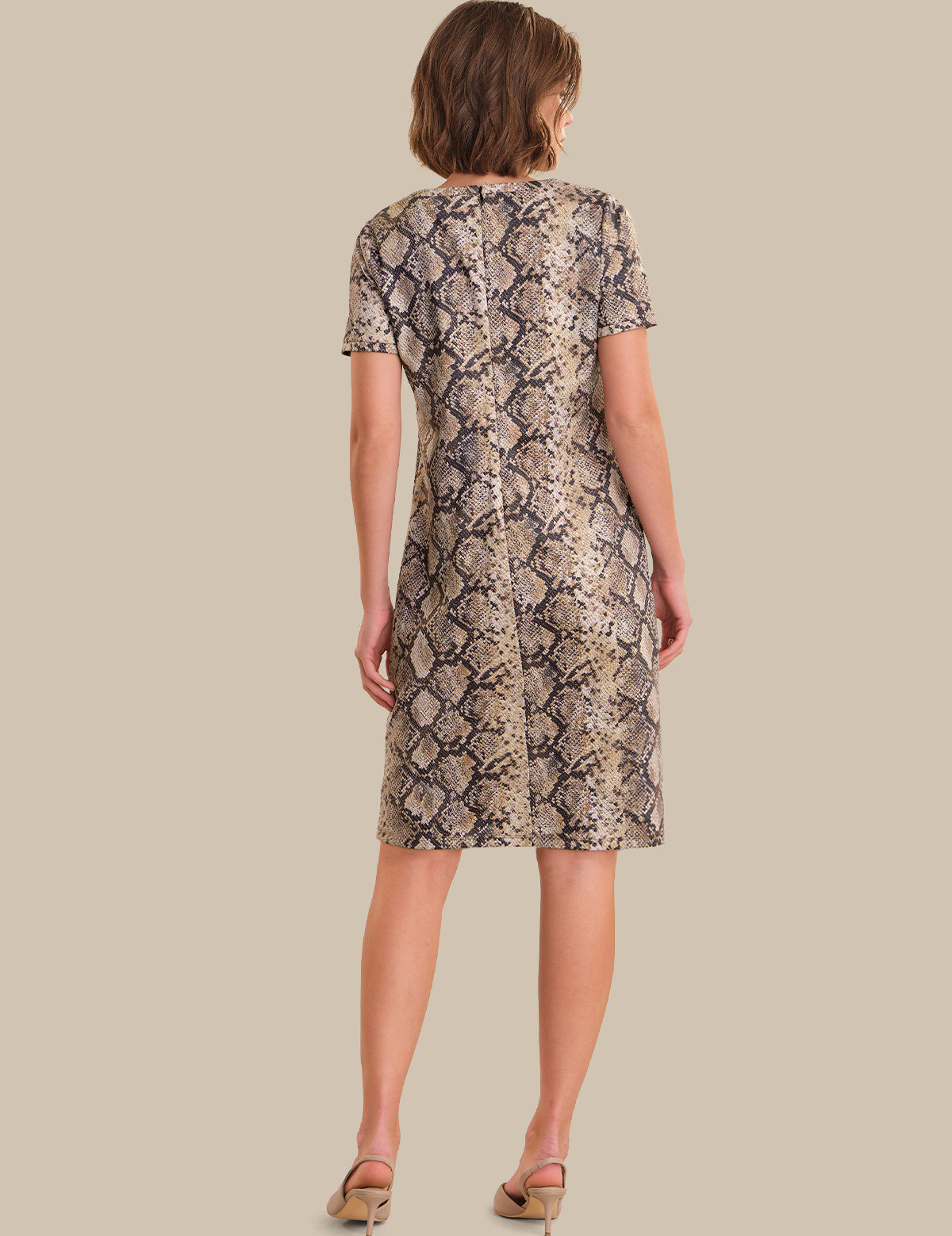 Woman wearing a snake print dress on a beige background