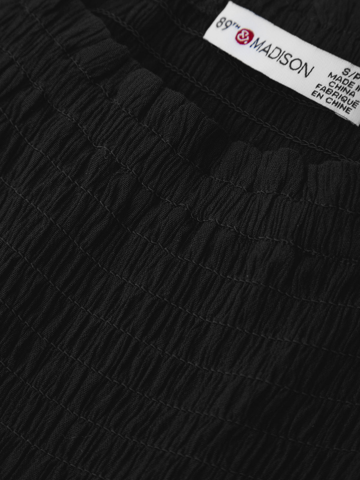 Close-up of black textured fabric with a brand label in the corner.