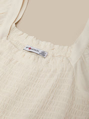 Close-up of a beige garment with a label on a plain background