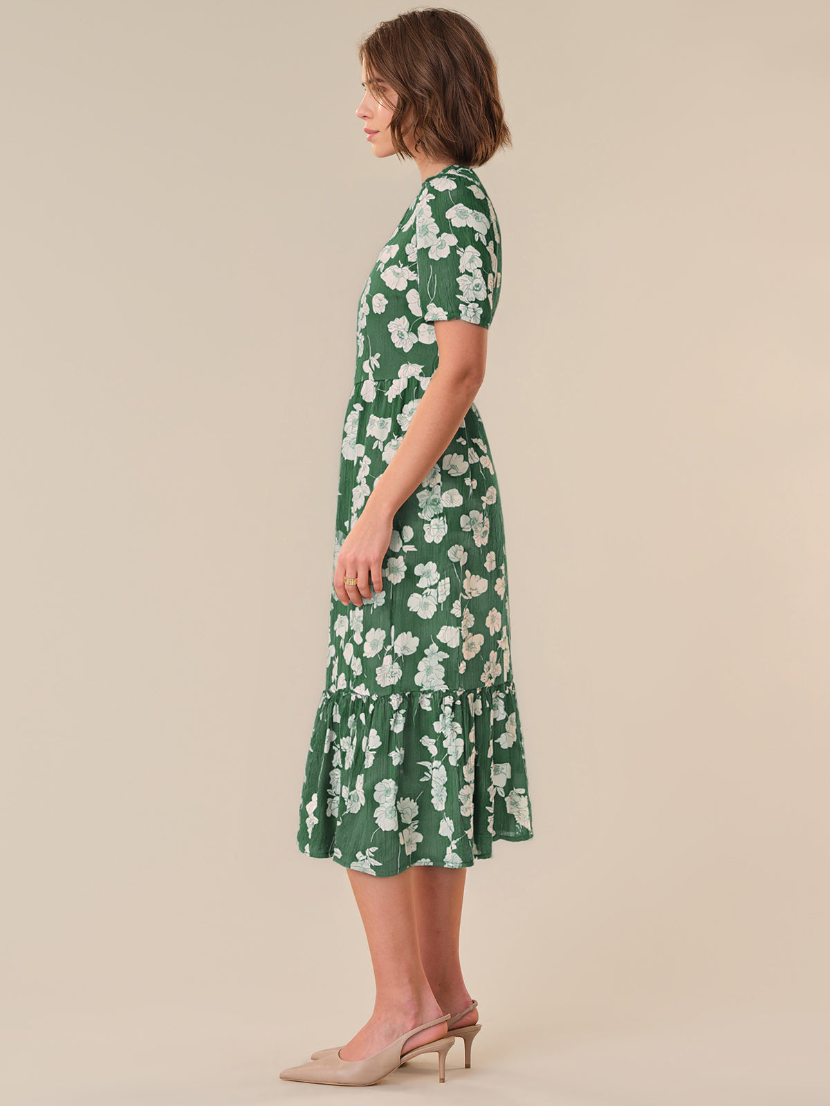 Woman wearing a green floral dress on a beige background
