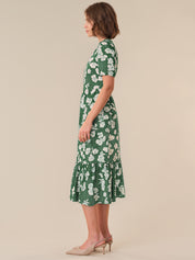 Woman wearing a green floral dress on a beige background
