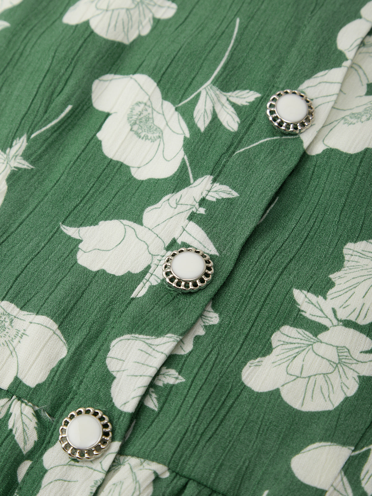 Green fabric with white floral pattern and silver buttons