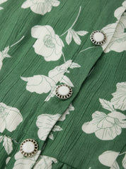 Green fabric with white floral pattern and silver buttons