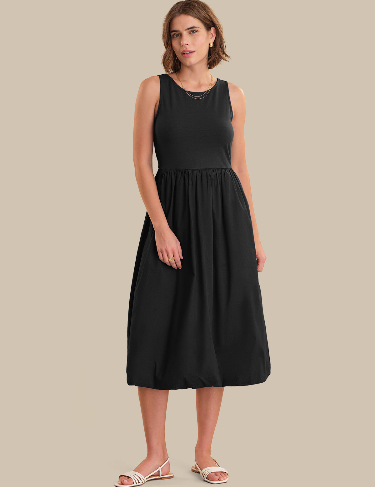 Woman wearing a black sleeveless dress on a beige background
