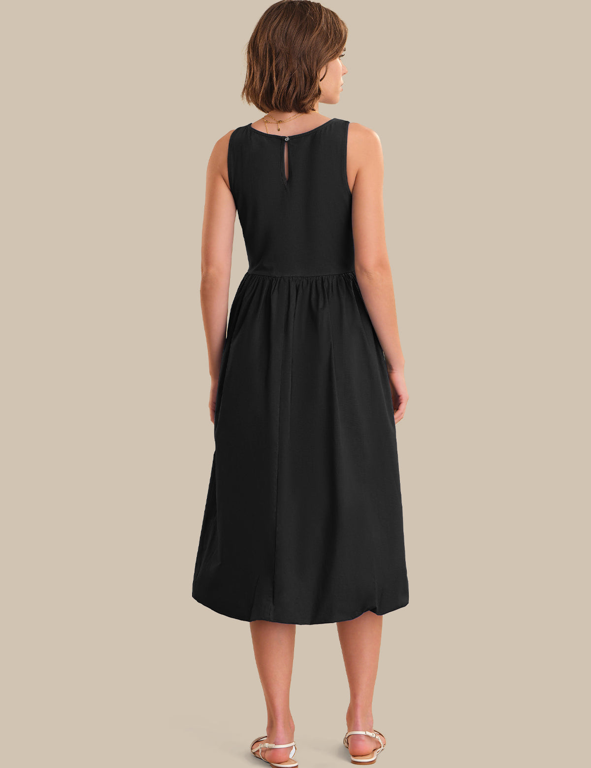 Woman wearing a black sleeveless dress on a beige background