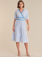 Woman wearing a blue and white striped dress with a belt on a beige background