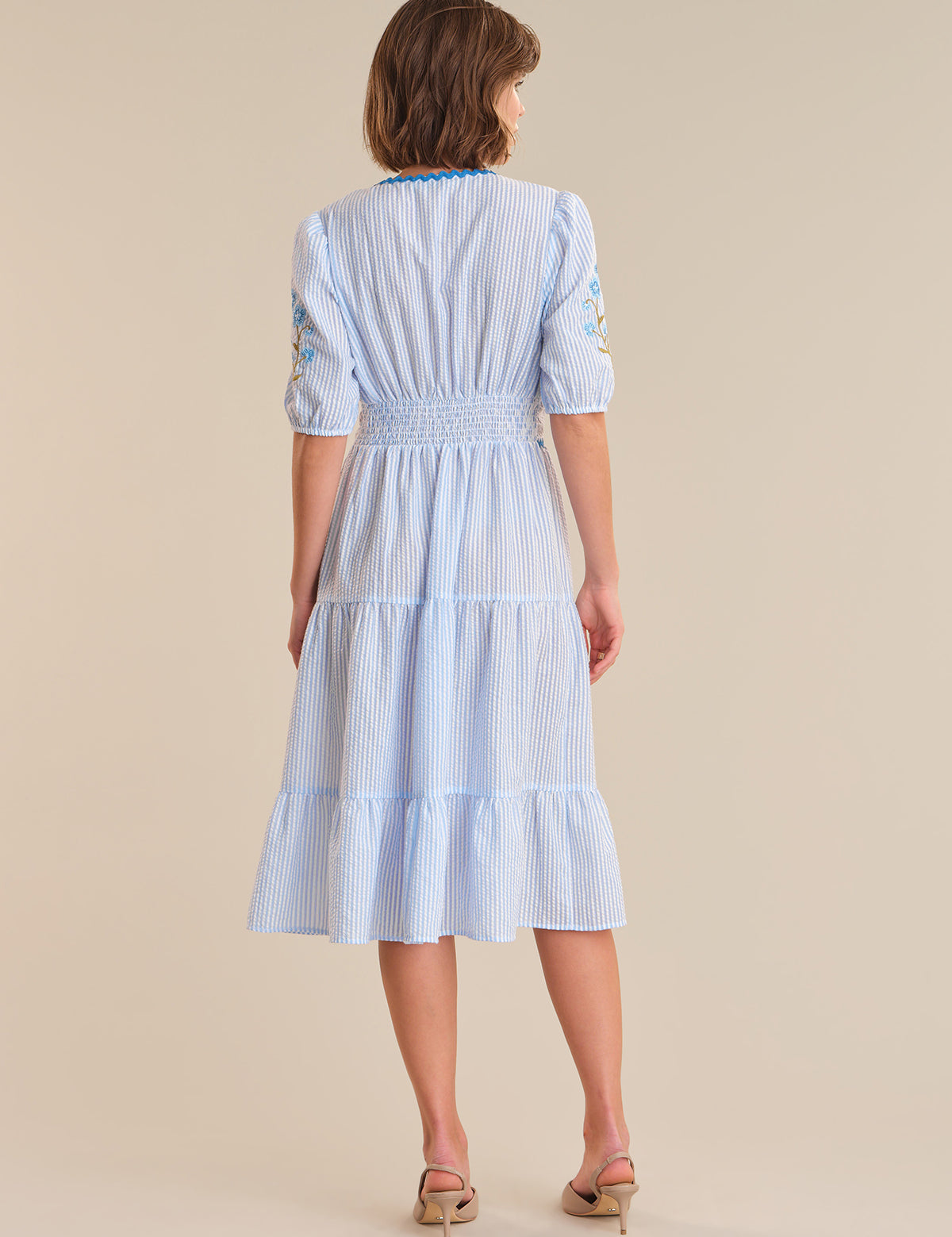 Woman wearing a blue and white striped dress on a beige background