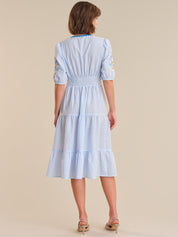 Woman wearing a blue and white striped dress on a beige background