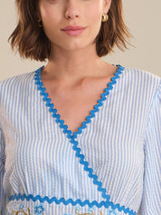 Close-up of a woman wearing a blue and white striped dress with decorative trim.