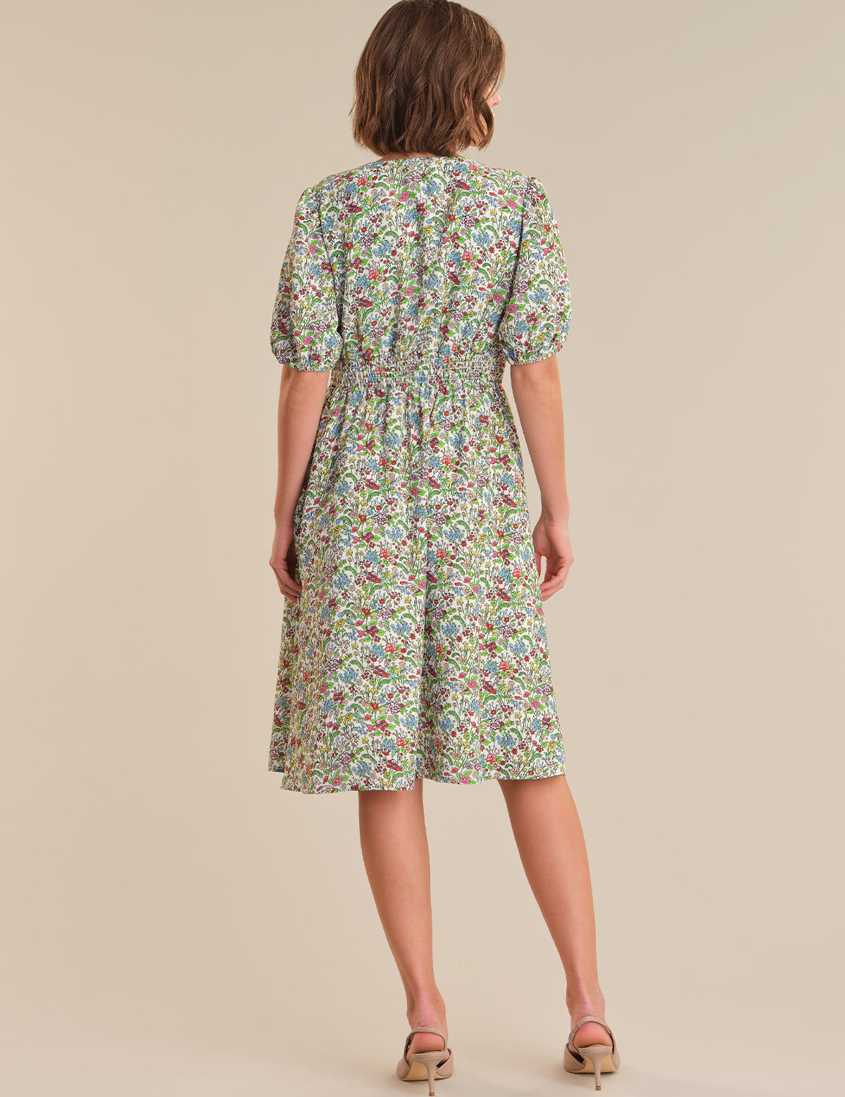 Woman wearing a floral dress on a beige background