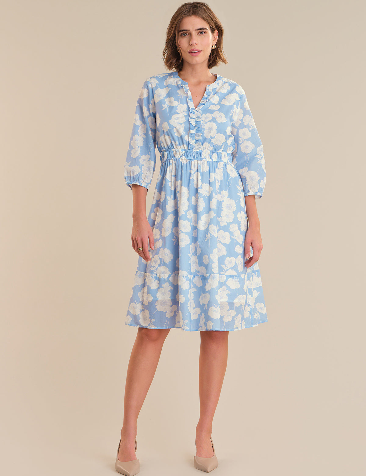 Woman wearing a blue floral dress on a beige background