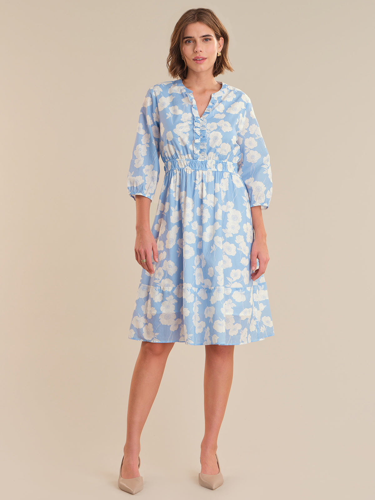 Woman wearing a blue floral dress on a beige background