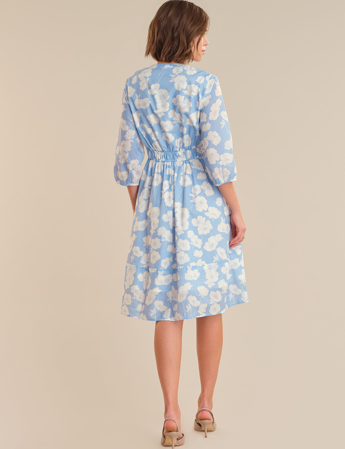 Woman wearing a blue floral dress on a beige background
